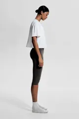 Remera deportiva blanca de corte boxy, confeccionada en tejido funcional DryMove™ que ayuda a absorber el sudor. Tiene cuello redondo, mangas cortas con hombros caídos y bajo recto.