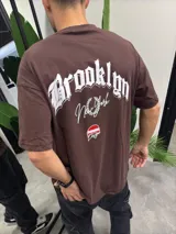 Remera marrón de algodón con estampado blanco en la espalda que dice "Brooklyn New York" y logo de "Bohemian Design" en rojo.