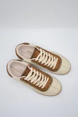 Zapatillas bajas color beige con detalles en marrón y cordones blancos.