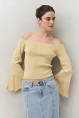 Top tejido color beige con escote off-shoulder y mangas largas acampanadas.