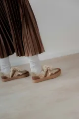 Championes acordonados color beige y dorado con suela marrón.