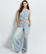 Pantalón de jeans azul de corte wide leg, tiro medio, con cintura de diseño traspasado y cierre tradicional.