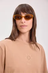 Remera color tostado de algodón con cuello redondo y mangas cortas. Estampado pequeño en el centro del pecho con un sol y texto.