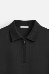 Polo gris de punto con cuello solapa y cierre frontal de cremallera. Corte regular fit, manga corta y acabados en rib.