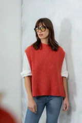 Chaleco de punto grueso color coral, con cuello alto y sisas amplias.