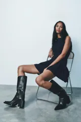 Bota de cuero negra con caña alta, punta cuadrada y tacón ancho.