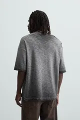 Camiseta gris de punto con efecto lavado, corte holgado, cuello redondo y mangas cortas.