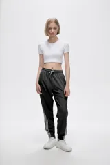 Pantalón de jogging color celeste con cintura elástica ajustable con cordón y puños elásticos. Presenta tres tiras verticales blancas en la parte inferior de la pierna.