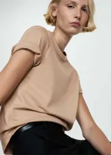 Remera color beige de corte recto, cuello redondo y mangas cortas con dobladillo.