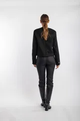 Chaqueta negra con textura, cuello redondo, cierre frontal con botones dorados y bolsillos delanteros con solapa y botón dorado.