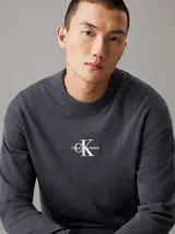 Sweater gris oscuro de punto de algodón con cuello redondo, puños y bajo acanalados. Presenta el logo de Calvin Klein bordado en el pecho.