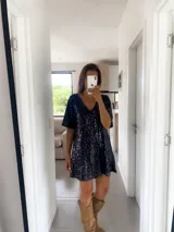 Vestido corto negro con lentejuelas, escote en V y mangas cortas.