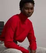 Blusa de punto color blanco, con cuello alto, manga larga y diseño liso.