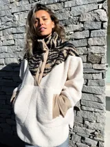 Buzo de polar color crudo con cuello alto y cierre de botones a presión. Parte superior con estampado animal print de cebra en tonos beige y negro.