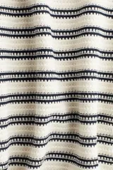 Vestido largo de punto texturizado a rayas horizontales en blanco y negro. Tiene cuello redondo, mangas largas y tajo lateral pronunciado.