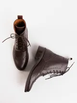 Bota corta de cuero color marrón claro, con cordones y detalles de perforaciones. Tiene un pequeño taco de madera.