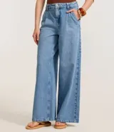 Pantalón wide leg de jeans azul claro, con cintura alta, trabillas, cierre con botón y cremallera, bolsillos y pliegues delanteros.