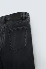 Pantalón de jean negro con corte flare y estilo baggy, con cinco bolsillos, efecto lavado y cierre frontal con botones.
