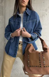 Sobrecamisa de denim azul con bordados florales en cuello y hombros, cierre frontal con botones azules y corte holgado.