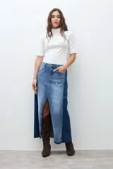 Falda larga de jean de tiro alto, con lavado medio y tajo frontal profundo. Presenta un diseño bicolor con paneles de denim de tonos ligeramente diferentes.