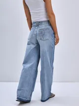 Pantalón de jean color beige, de corte wide leg, con bolsillos delanteros y traseros, y ruedo desflecado.