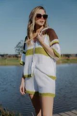 Conjunto tejido de algodón a rayas horizontales color blanco y marrón, compuesto por una camisa de manga corta con cuello polo y botones, y un short de tiro alto con cintura elástica. Incluye cordón de cuero marrón.