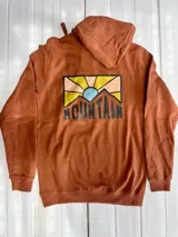 Buzo hoodie color ladrillo con estampado en la espalda de montañas y sol.