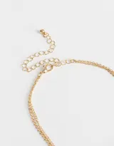 Collar corto dorado de doble cadena, una con cuentas esmaltadas azules y otra con dijes circulares. Incluye dije de caracol dorado.