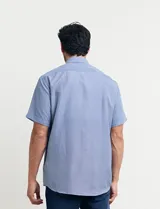 Camisa celeste con microestampado geométrico, de corte clásico, manga corta, cuello abotonado y bolsillo en el pecho.