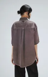 Camisa manga corta color gris con efecto desgastado, corte holgado y cierre frontal con botones.