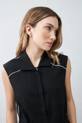 Mono negro de lino con corte recto, cuello camisero, sin mangas y vivo blanco en contraste en cuello, sisas y laterales.