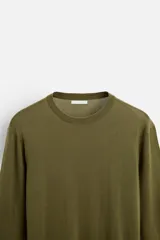 Jersey negro de lana con acabado mercerizado, corte relaxed fit, cuello redondo y manga larga con terminaciones en rib.