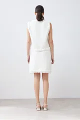 Falda corta color crudo tejida con textura acanalada horizontal y terminación desflecada en el ruedo.