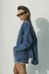 Camisa de denim azul con botones dorados, corte holgado, cuello clásico y bolsillos frontales.