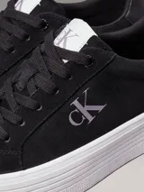 Zapatillas de ante negras con plataforma blanca y logo CK en el lateral.