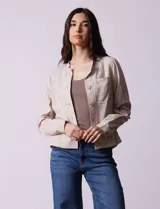 Chaqueta color beige de lino y rayón, con cuello mao, cierre frontal con botones y bolsillos delanteros.