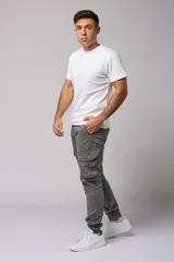 Pantalón cargo color beige de gabardina, con corte ajustado, bolsillos laterales con fuelle y puños elásticos en los tobillos.