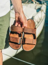 Sandalias Aura de cuero color marrón, con tiras ajustables con velcro y plantilla acolchada.