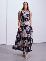 Vestido maxi de seda fría con estampado floral en tonos beige y azul marino, de la marca Sandra Darren. Tiene cuello alto entrelazado con abertura ojal y aplique metálico.