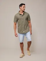 Camisa de algodón blanca de manga corta, con cuello abotonado y botones frontales.