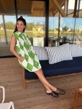 Vestido camisero corto con estampado de rombos en tonos beige, marrón y blanco. Tiene cuello camisero, cierre frontal con botones y corte holgado.