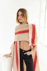 Ruana artesanal color beige con rayas horizontales rojas y amarillas, y flecos en el borde inferior.