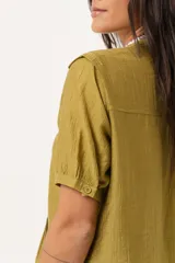 Blusa color verde oliva con cuello mao, mangas cortas abullonadas y cierre frontal con botones.