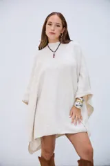 Poncho de punto color crudo, con cuello redondo y diseño holgado.