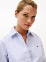 Camisa celeste a rayas verticales blancas, de corte amplio, con cuello inglés y logo bordado en el pecho.