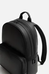 Mochila negra con acabado grabado, compartimento principal con cierre de cremallera, bolsillo interior con cremallera, bolsillo frontal con cremallera, asa de mano, dos asas de hombro ajustables, parte posterior acolchada y banda de sujeción para equipaje.