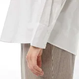 Camisa blanca de corte holgado, manga larga y cuello clásico.