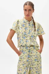 Camisa amarilla de lino con estampado floral en tonos azules, cuello mao y mangas cortas con volados. Cierre frontal con botones. Marca Francesca.