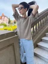 Remera tejida color marrón con hilado 100% algodón y cintas de piedras aplicadas en cuello y mangas.