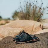 Sandalias bajas de cuero vacuno color negro, con suela de goma y horma de punta redonda. Producto de horma chica, se recomienda pedir un talle más.